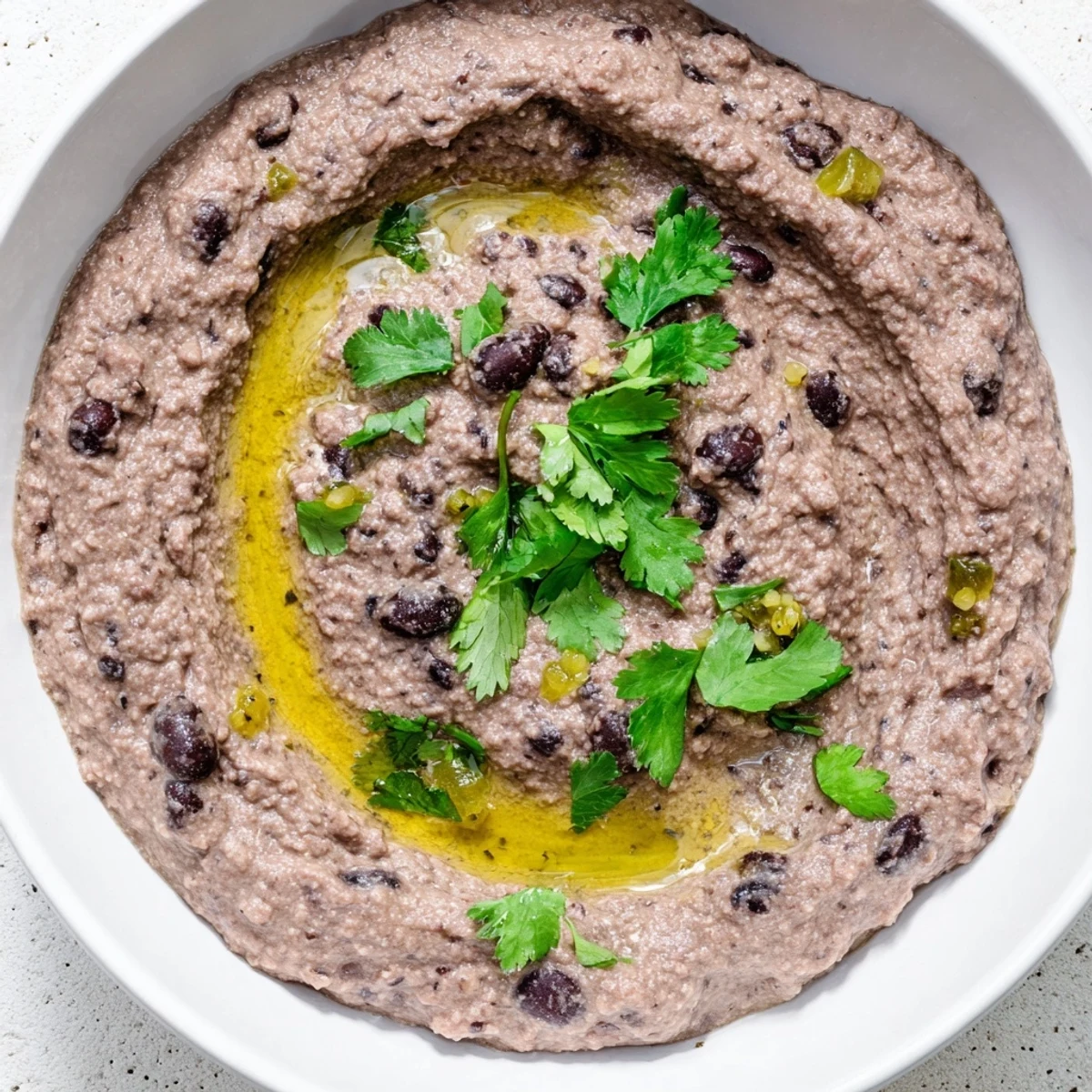 Spicy black bean dip served in a rustic bowl with blue corn tortilla chips for dipping.  