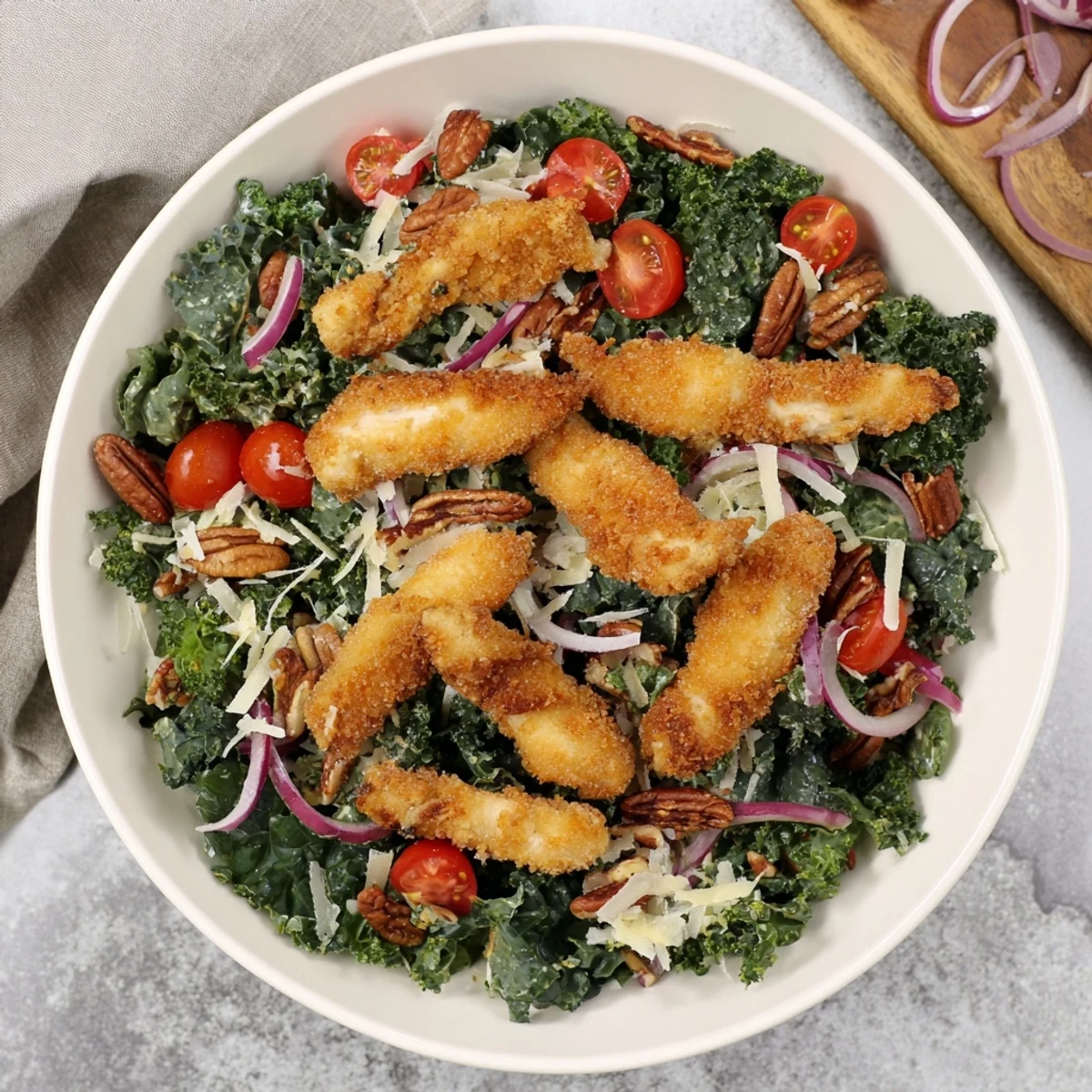 A rustic plate of Crispy Chicken Kale Salad with fresh kale, red onion, and drizzled tangy maple-Dijon dressing, ready to serve.