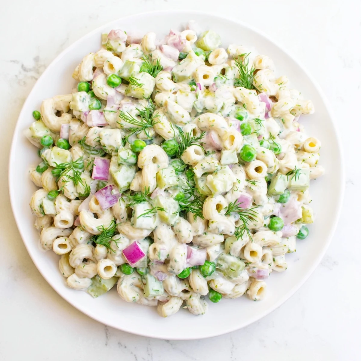 Vibrant green peas and crunchy dill pickles tossed in creamy dressing make this Creamy Dill Pickle Pasta Salad a picnic favorite.  