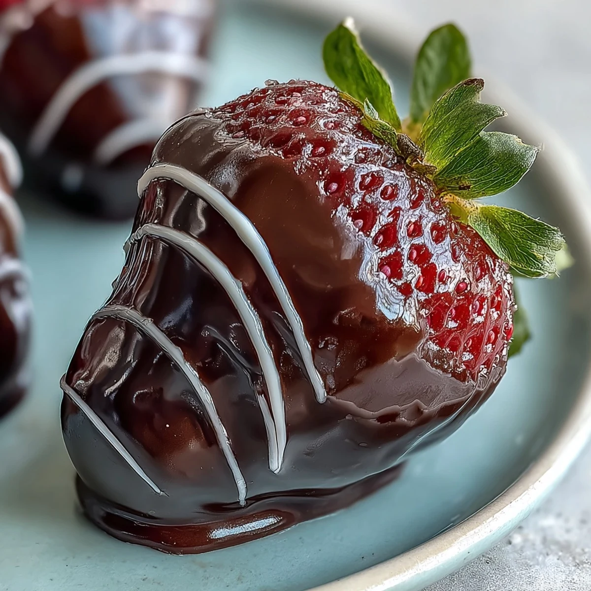 Decadent chocolate-covered strawberries drizzled with white chocolate, garnished with chopped pistachios on a white marble countertop.