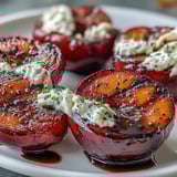 Perfectly caramelized Balsamic-Goat Cheese Grilled Plums garnished with fresh mint and black pepper for serving.  