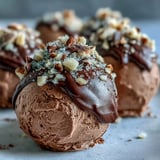 Decadent chocolate truffles coated in chopped nuts, resting on a marble surface, offering a gluten-free dessert bite.