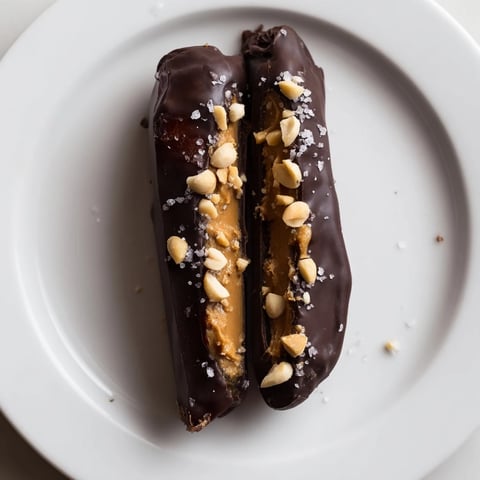 Delectable Chocolate Date Snickers, with creamy peanut butter centers, dipped in glossy dark chocolate, ready to be enjoyed.