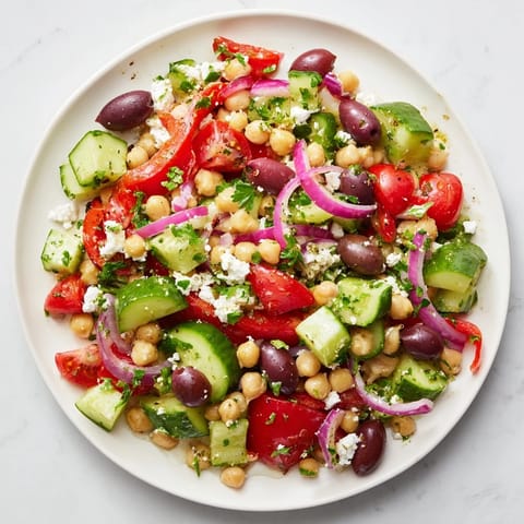 This image shows a colorful Fresh Mediterranean salad, featuring olives and chickpeas, ready to enjoy.
