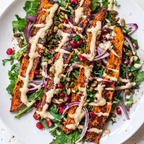 A close-up of a colorful Roasted Carrot Salad, boasting a creamy drizzle and toasted seeds.
