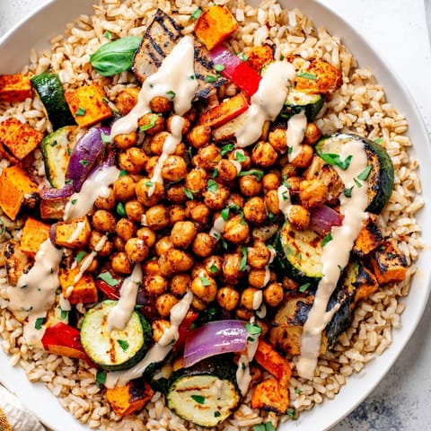 This vegan Roasted Chickpea Buddha Bowl features fluffy rice under a swirl of creamy tahini sauce.