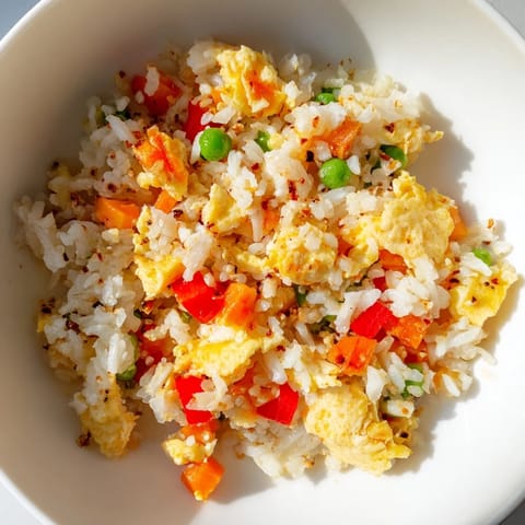 Fluffy scrambled eggs and colorful vegetables mixed into golden fried rice, ready to serve in a bowl.  