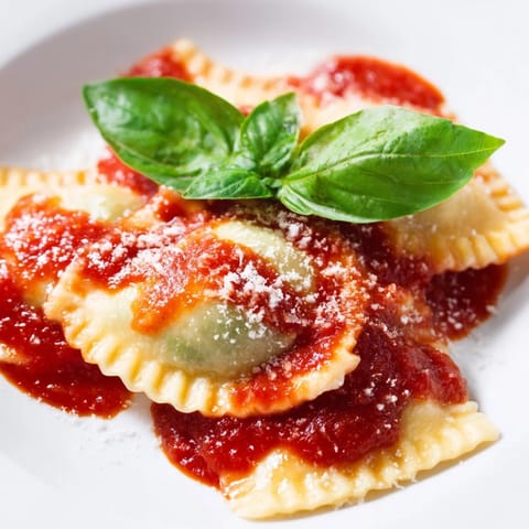 Steaming spinach ricotta ravioli plated with marinara, parmesan, and a glass of Pinot Grigio.