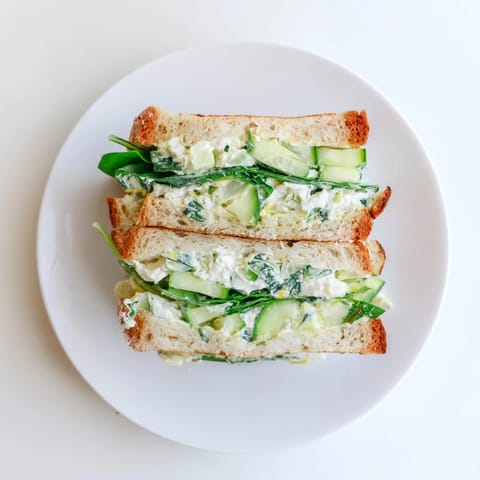 Crusty sourdough bread encases a vibrant, tangy whipped feta spring grilled cheese, layered with spinach and cucumber for a fresh bite.