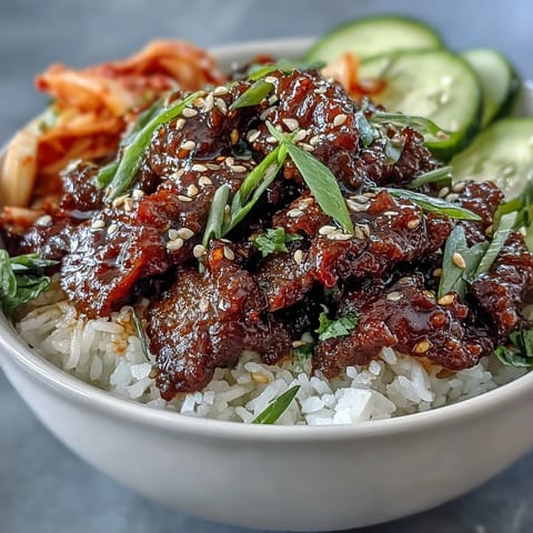 A colorful Korean Ground Beef Bowl features spicy ground beef, tangy kimchi, cucumber, and carrots served over steamed rice.