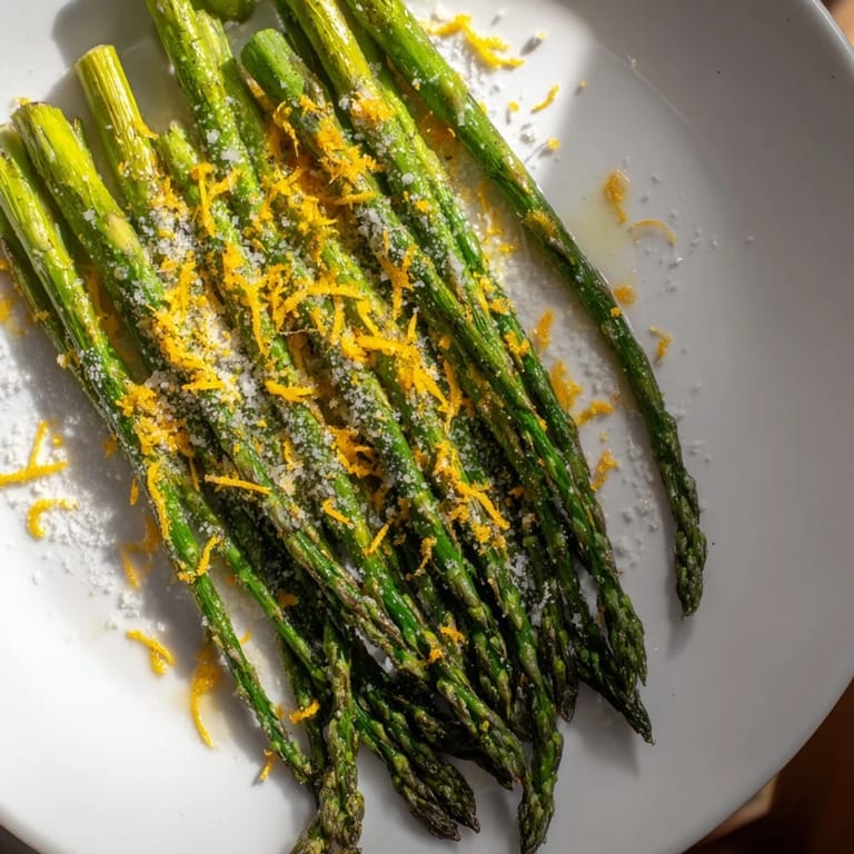 Picture of tender roasted asparagus spears, generously sprinkled with cheese on a baking sheet.