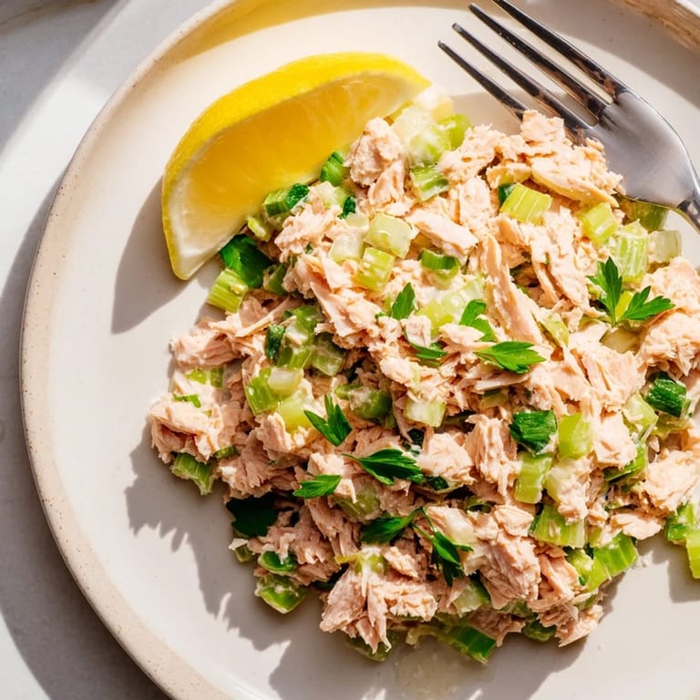 Vibrant plated Spicy Zesty Tuna Salad garnished with parsley and lemon, ready to serve with a fork nearby.