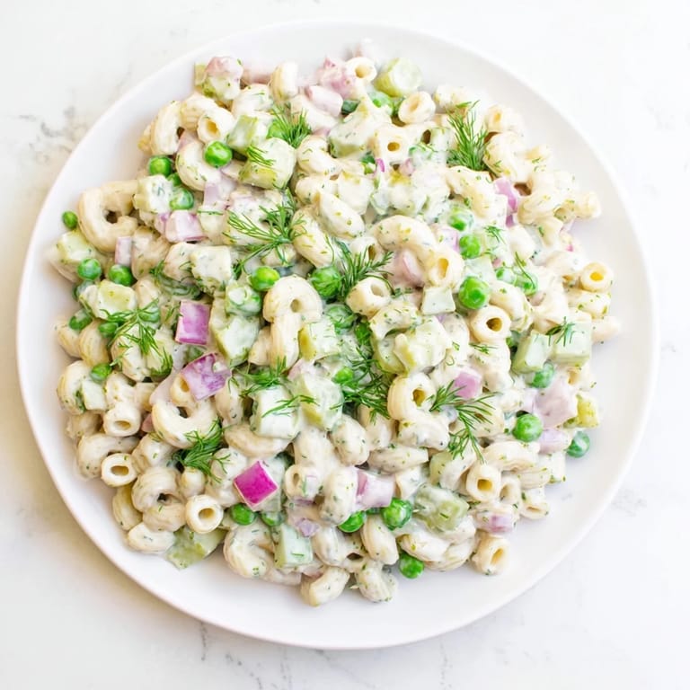 Vibrant green peas and crunchy dill pickles tossed in creamy dressing make this Creamy Dill Pickle Pasta Salad a picnic favorite.  