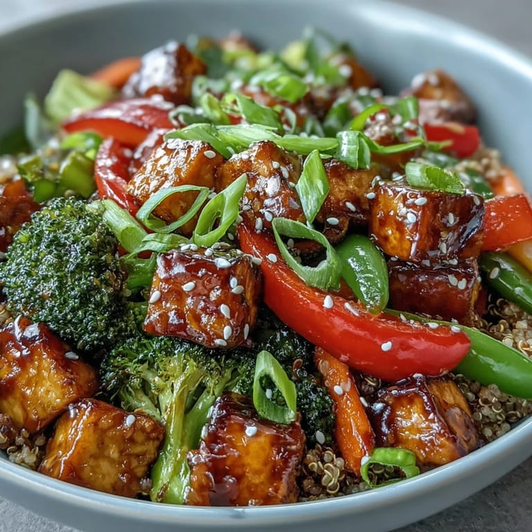 A colorful vegan quinoa vegetable teriyaki bowl garnished with green onions and sesame seeds, served as a wholesome main dish.