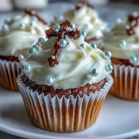 Mini First Communion Cupcakes with Rosary Fondant Toppers: A close-up view of delicate vanilla cupcakes frosted with smooth buttercream and crowned with handmade fondant rosary toppers, perfect for sacred celebrations.