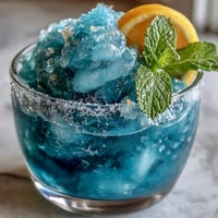 A vibrant blue raspberry lemonade slushie served in chilled glasses with sugared rims and fresh mint.